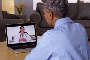 老年妇女主持视频访问与医疗保健提供者在客厅。